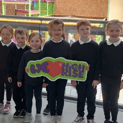 School children smiling while holding a 'we love High Rise' sign