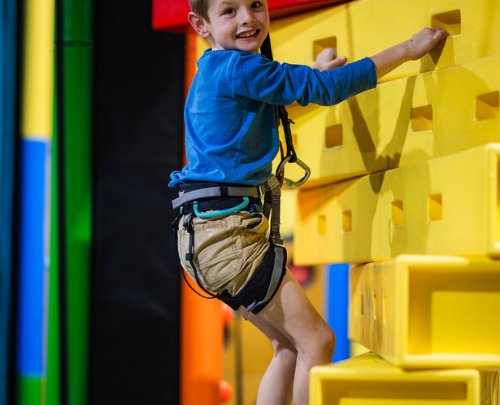 Young boy smiling at the camera while on a climbing challenge at High Rise Lisburn