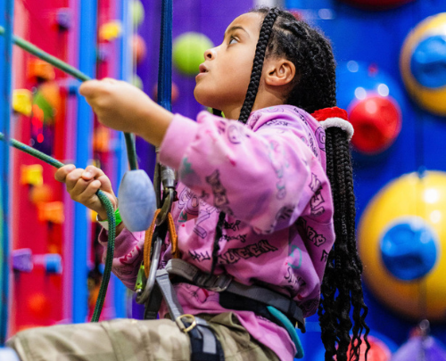 Young girl focusing hard on a climbing challenge at Clip in Clip at High Rise Lisburn